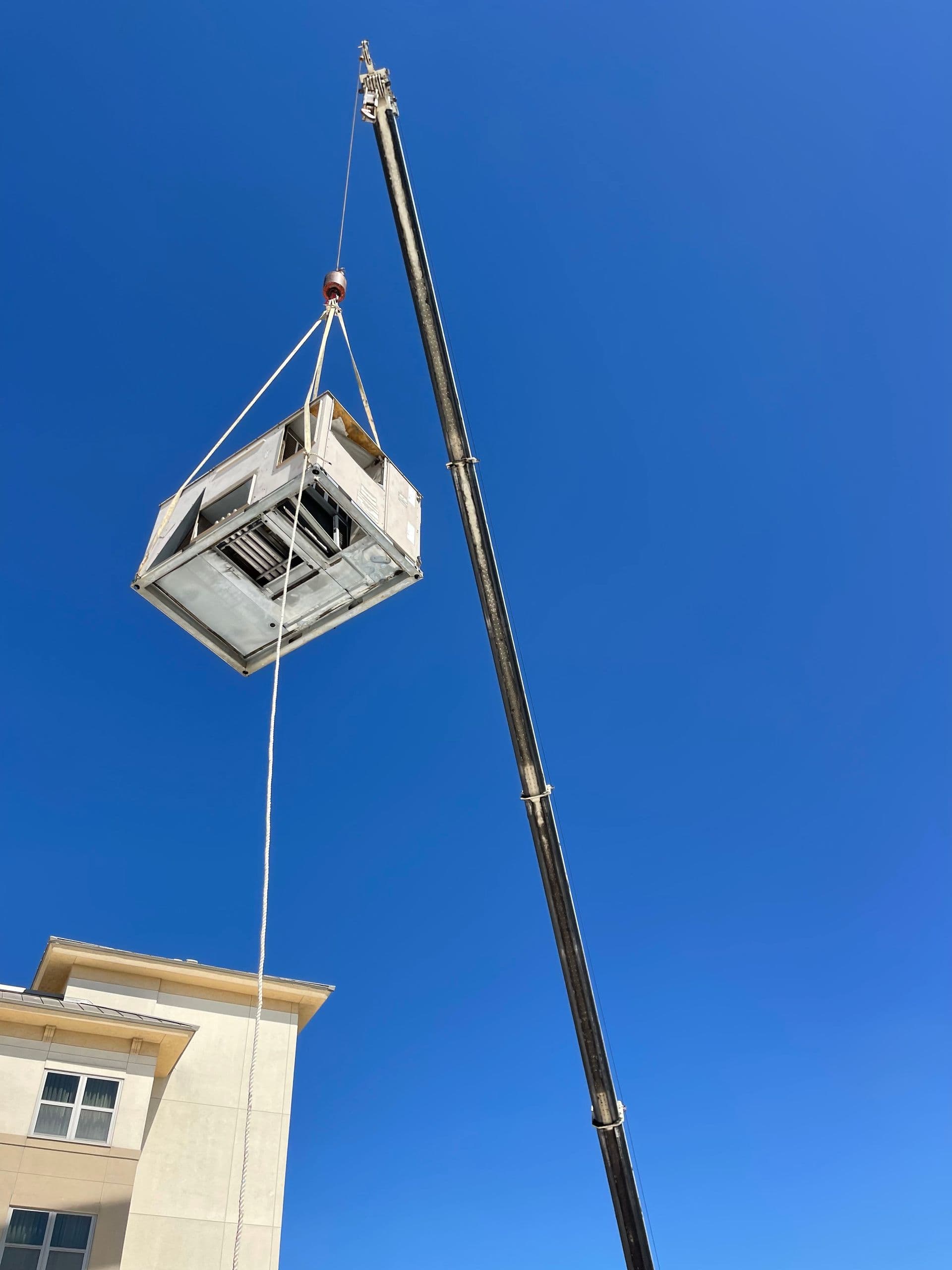 Rooftop HVAC unit being lifted by crane